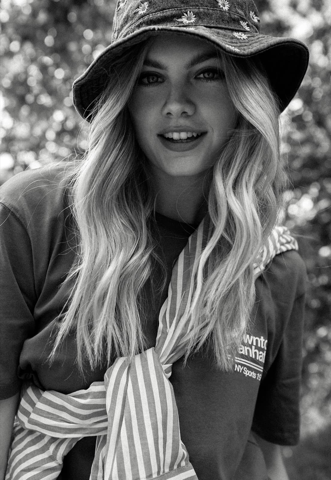 Soft blonde waves beneath a bucket hat.